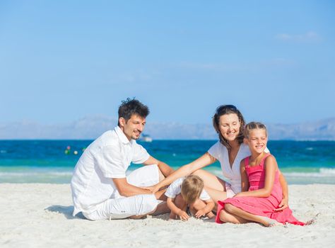 Family of four having fun on tropical beach