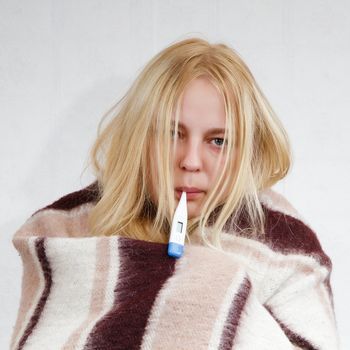 girl with a thermometer, wrapped in a blanket