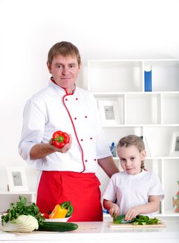 portrait of father and daughter cooking salad together in the kitchen