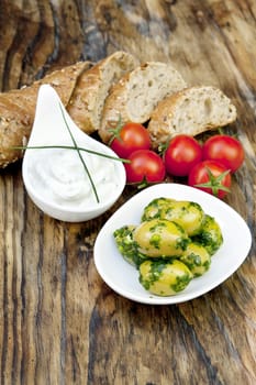 green olives with fresh bread and herbs on wooden background