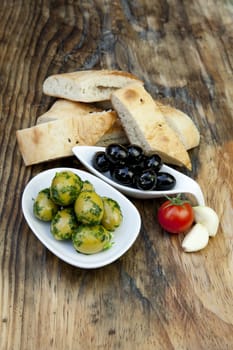 green olives with fresh bread and herbs on wooden background