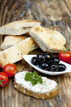 green olives with fresh bread and herbs on wooden background