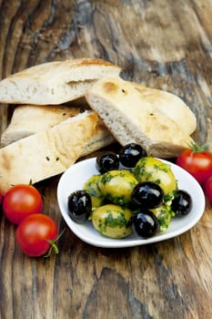 green olives with fresh bread and herbs on wooden background