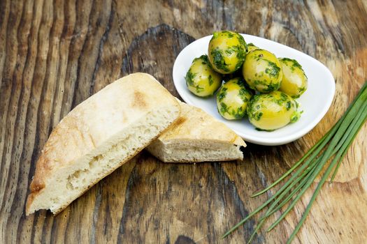 green olives with fresh bread and herbs on wooden background