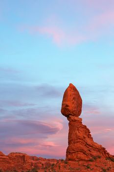 Arched park balancing rock at end of sunset against dramatic sky