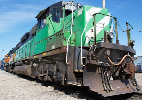 Green and weight freight train with blue sky background