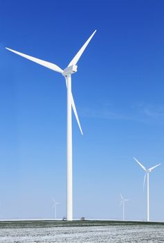 Image of a field with windturbines covered by snow in winter.