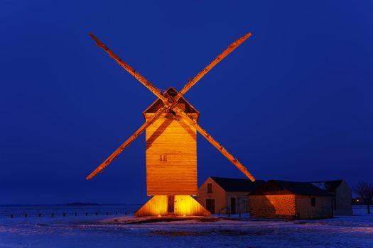 Night image of an old traditional wooden windmill in a field covered by snow.This windmill is The big windmill from Ouarville from Eure&Loir regon of France.