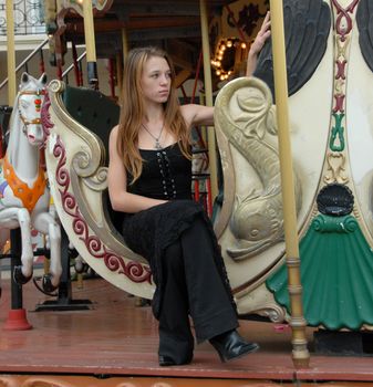 young teenager in a children carousel: pretty girl
