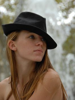 young teenager near a fountain with a black hat
