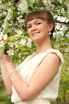 beautiful young brunette woman with the apple tree on a warm summer day