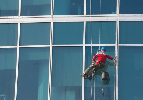 Climber - window cleaner perform the work at wall of an office building