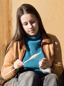 Girl spins a yarn of wool sitting outside on a sunny day