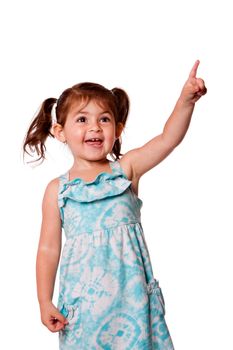 Cute little toddler girl pointing up wearing blue dress and pigtails in hair, isolated.