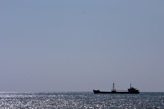 cargo ship on a background of horizon of blue waves of ocean and the sky