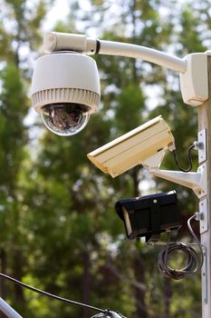Two surveillance video camera and an emergency light are mounted to an outdoor pole for security.