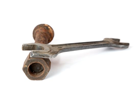 Wrench and rusty bolt with nut on a white background