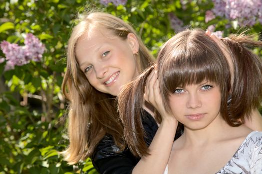 Two girls of the teenager against a blossoming lilac
