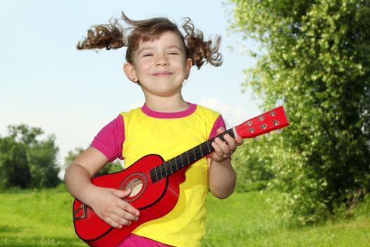 happy little girl play guitar outdoor