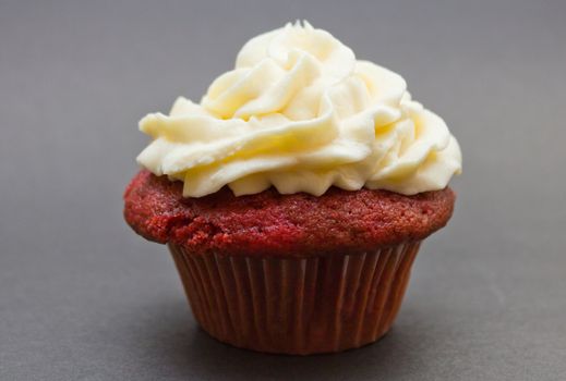 Red velvet cupcake with buttercream icing isolated on black.
