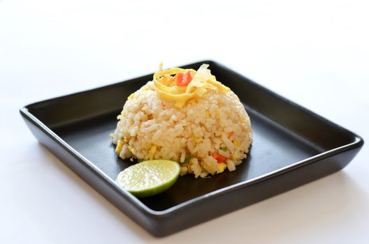  fried rice served with omelet  slice  and lemon slice on black dish
