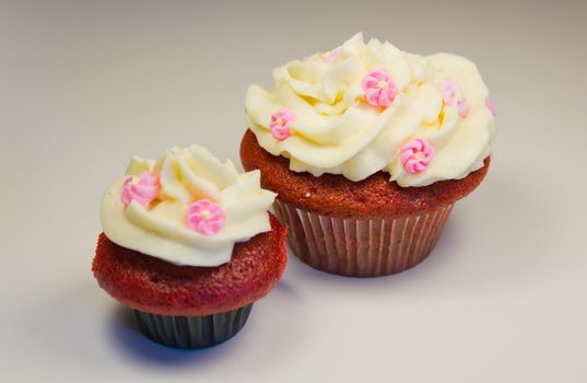 Red velvet cupcakes with buttercream icing with flower decorations isolated on white.
