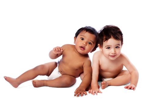 Two cute adorable multi-ethnic babies sitting together, childhood concept, on white.