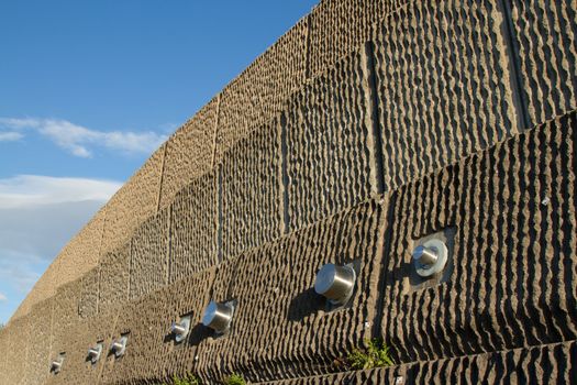 An engineered precast concrete retaining wall with stainless steel reinforcing pins against a blue sky.