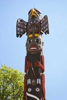 Totem pole on blue sky background and green tree