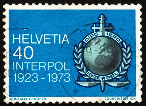 SWITZERLAND - CIRCA 1973: a stamp printed in the Switzerland shows Interpol Emblem, 50th anniversary of International Criminal Police Organization, circa 1973