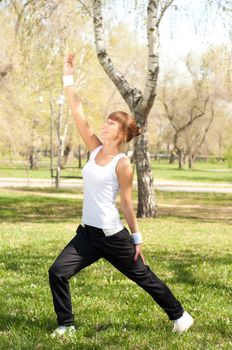 beautiful young woman performs a sport exercises in the park