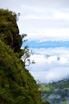 Mountain by green grass and cloudy blue sky