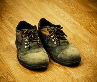 pair of old used trekking boots on the wood background