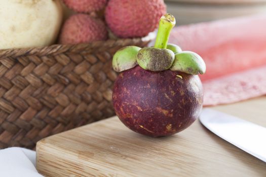 Subtropical mangosteen fruit on cutting board.