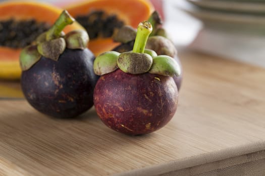 Three fresh tropical mangosteen on cutting board