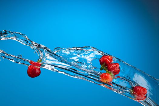 water splash with ripe red strawberry over blue background