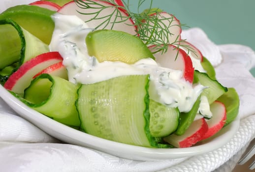 Cucumber salad with radish and avocado cream sauce and dill