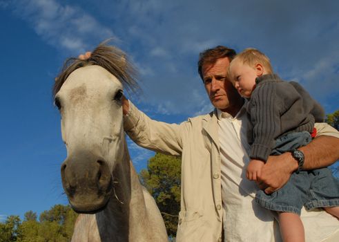 a father and his son stroking a gray horse