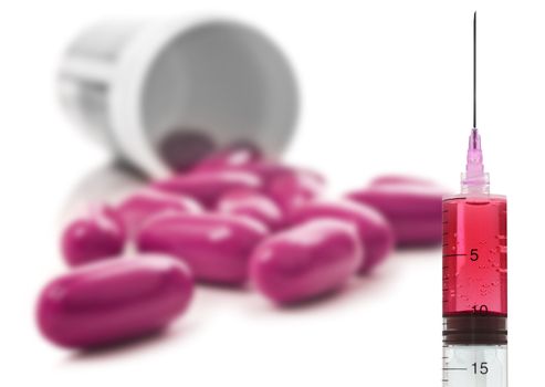 Pink pills an pill bottle on white