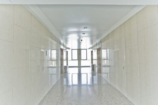 An empty office corridor with a bright light at the end of the hallway