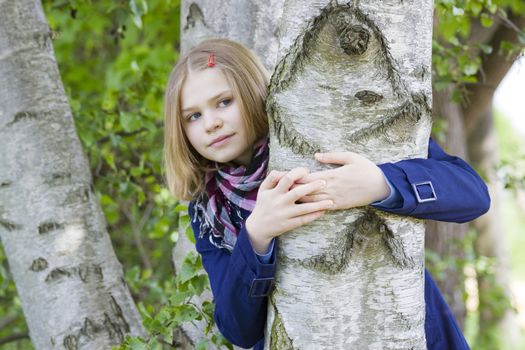 Girl hugging tree trunk and smiling 