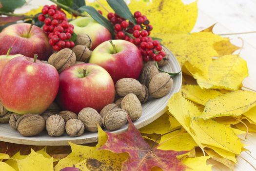 arrangement of autumn leaves and red apples and walnuts