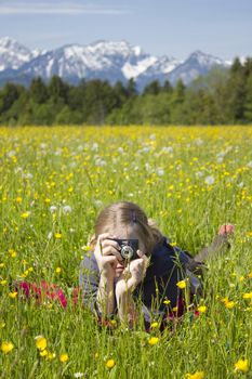 young girl taking photos by digital camera in the mountains