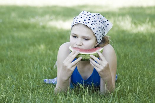 cute little girl eating watermelon on the grass  