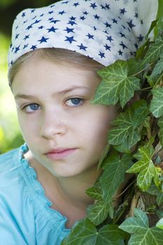 Portrait of young girl standing near tree at summer green park