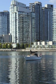 A sailboat & modern skyscrapers in Vancouver BC Canada.
