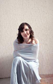 Young happy woman sitting in elegant dress.