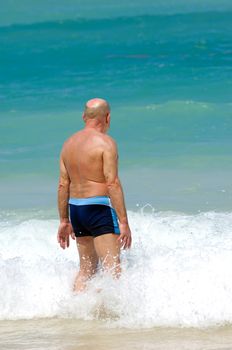 A senior man is standing in the water about to swim. Beach at Punta Cana, Dominican Republic.