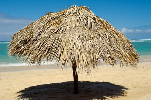 Parasol made out of palm leafs on beach.