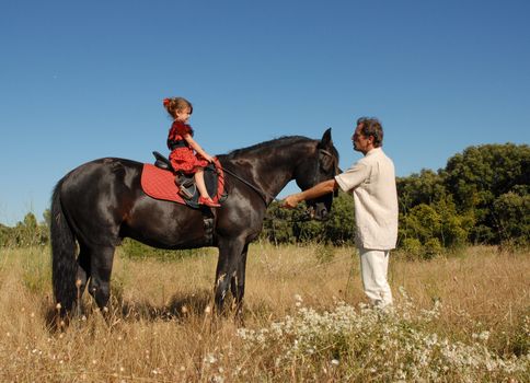 a father learning to his daughter to riding on a horse